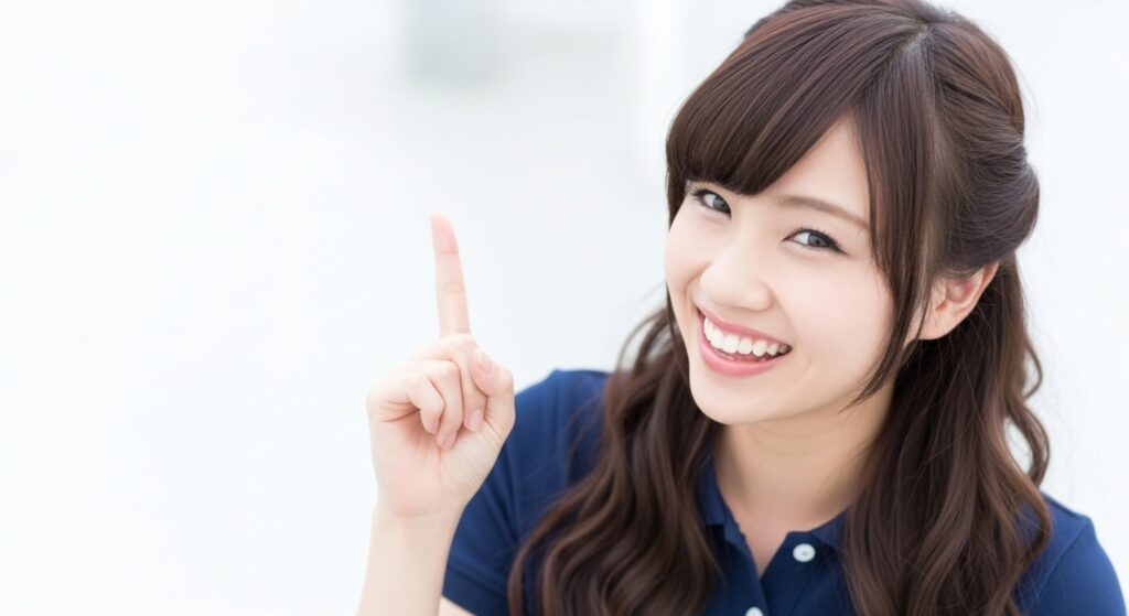 若い女性介護職員が笑顔で人差し指を立てている場面。ポイントの提示や注意喚起、ケアのコツを伝える導入カットとして使用できるイメージ。