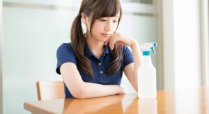 テーブルに置かれた除菌スプレーをじっと見つめ、衛生管理について考えを巡らせる女性スタッフ