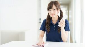 介護職員がPHS(業務用携帯)を手に持つ様子。ナースコール対応や職員間の連絡に使用する介護現場の通信手段