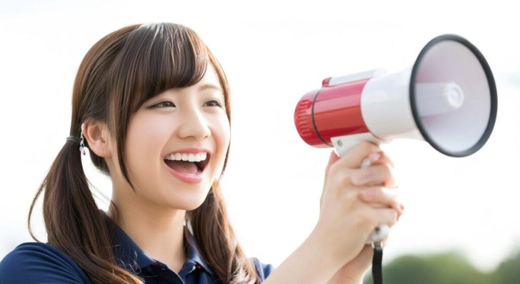 若い女性介護職員がメガホンを持ちながら笑顔で呼びかけている。お知らせや注意喚起を行うイメージ。